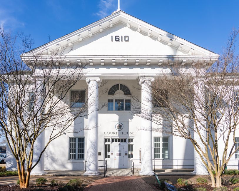 A white-columned historic Virginia courthouse under a blue sky